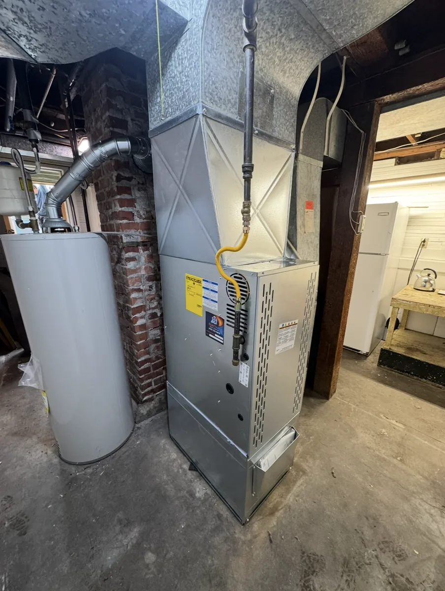 Replacement gas furnace in a basement with a newly fabricated sheet-metal plenum tied into the existing trunk line.